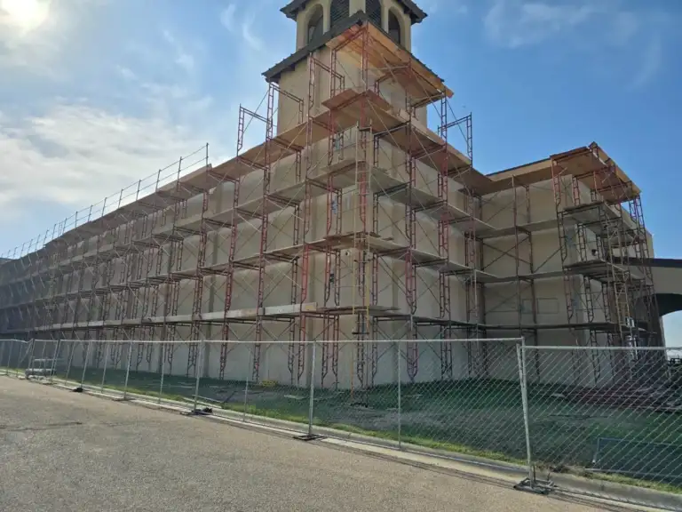 Commercial building with a bell tower fully scaffolded for stucco repair