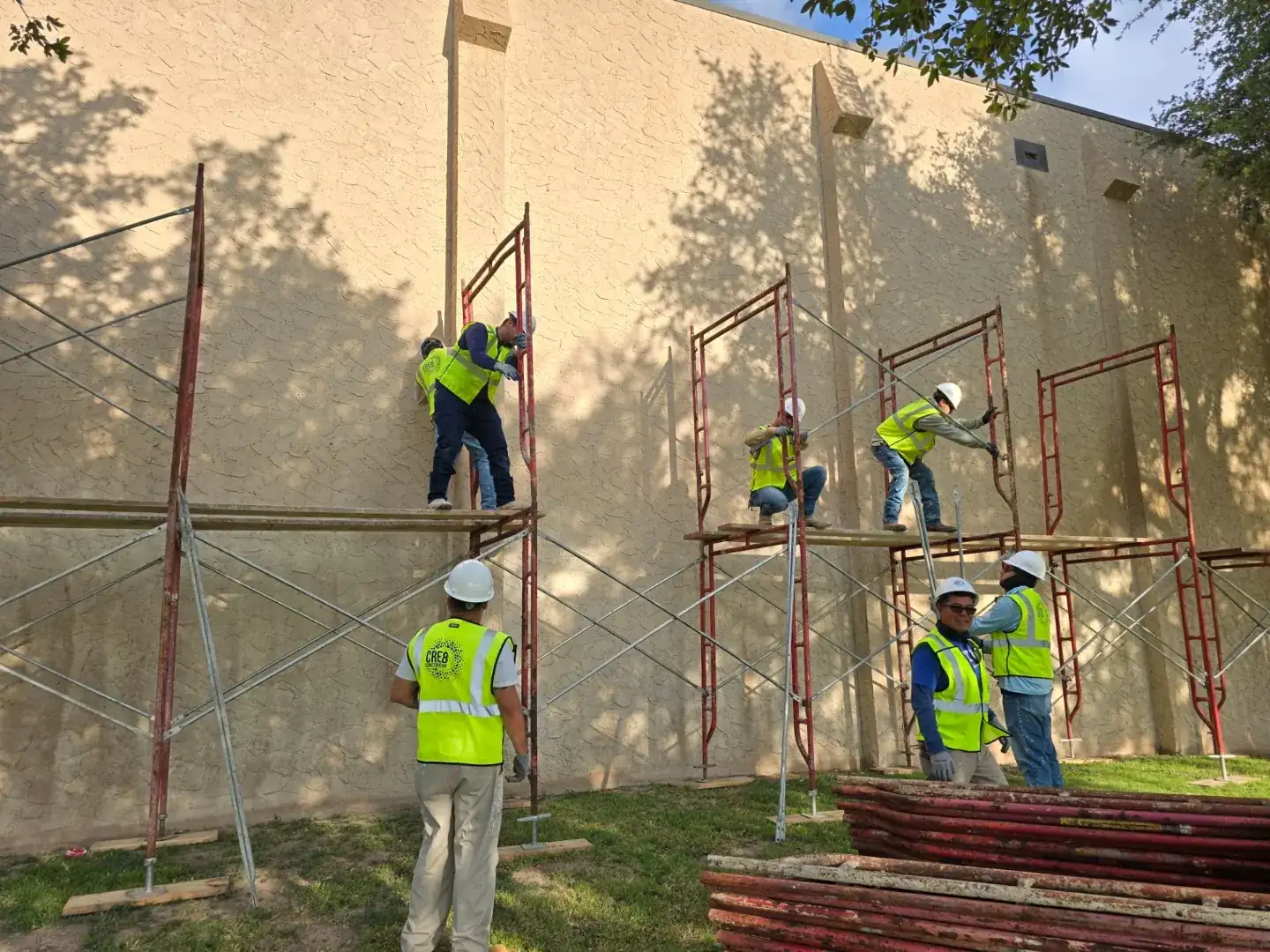 Cre8 Construction crew in hard hats and vests raising scaffold on a Texas job site